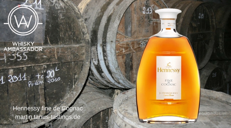 Eine Flasche Hennessy Fine De Cognac, im Hintergrund alte Fässer