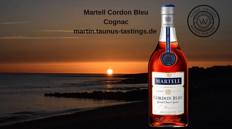 Eine Flasche Martell Cordon Bleu Cognac, im Hintergrund ein Strand in Frankreich