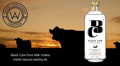 Eine Flasche Black Cow Pure Milk Vodka, im Hintergrund Kühe