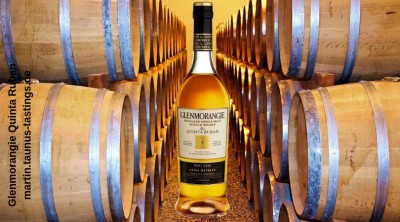 Eine Flasche Glenmorangie Quinta Ruban, im Hintergrund Whisky-Fässer