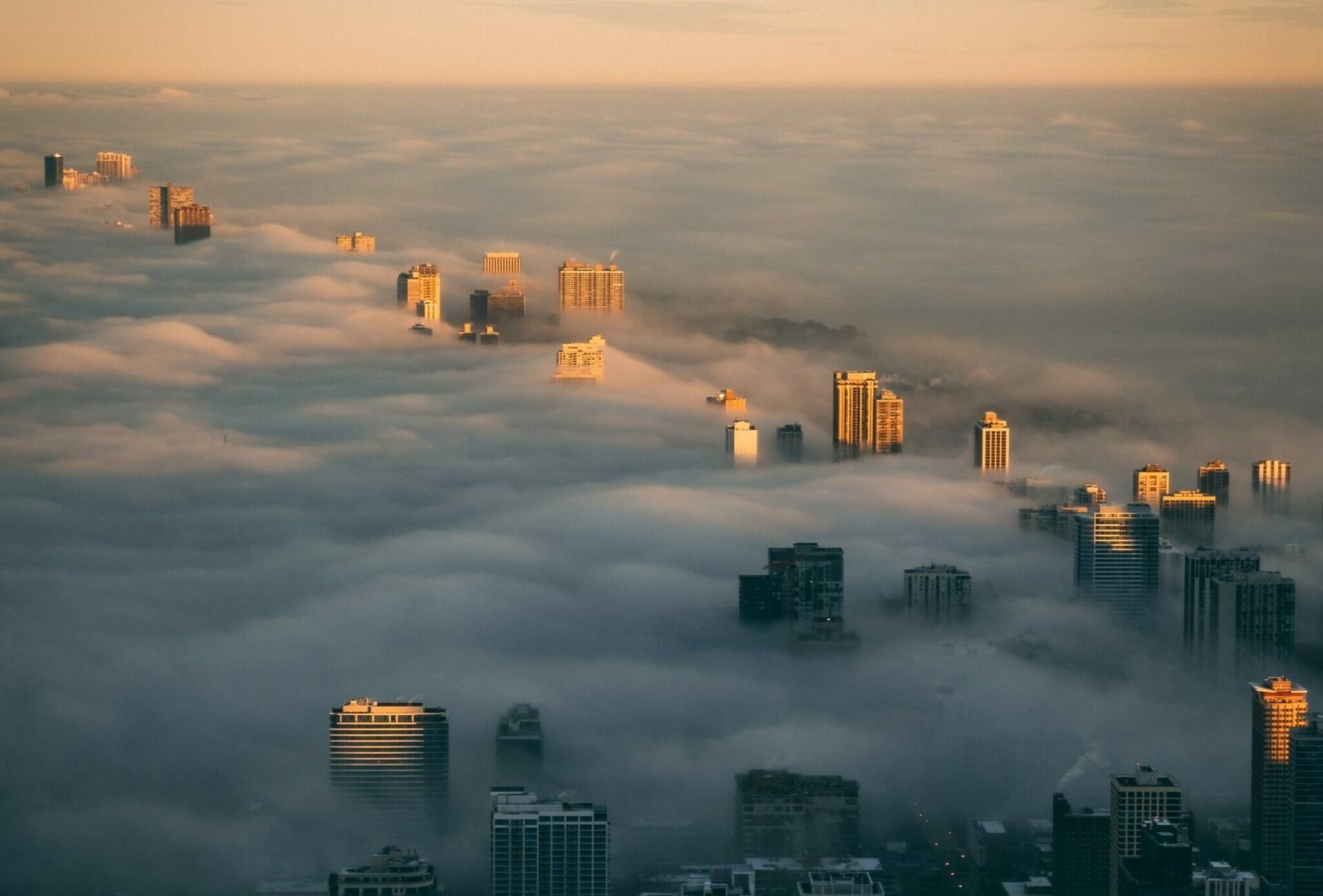 View from above of a city skyline at sunrise with a layer of fog adding a moody tone