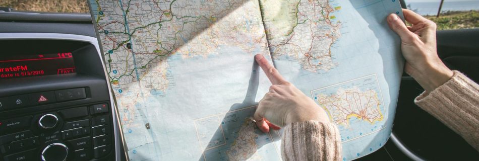 person wearing beige sweater holding map inside vehicle