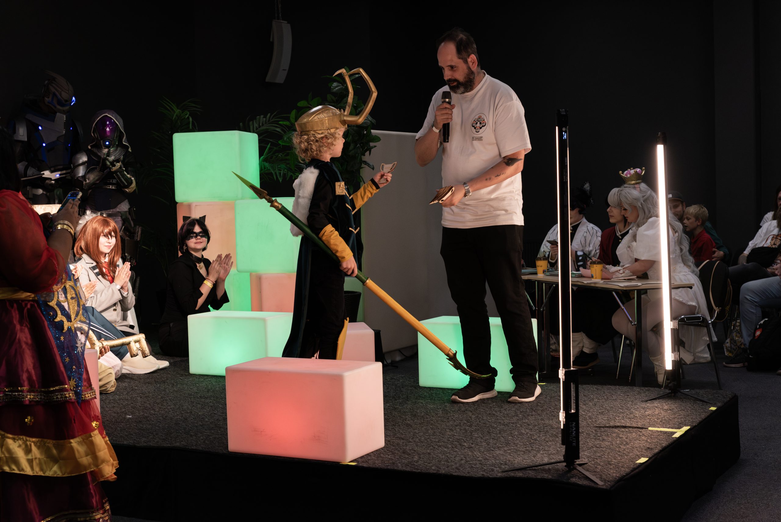 Award being handed to a young cosplayer on stage.