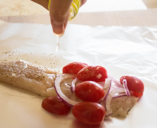 Placez 1 filet sur papillote. Mettrez les tomates cerises et oignons dans la première moitié du poisson.  Faites un peu d'huile de tournesol Migino sur le poisson. Salez et poivrez