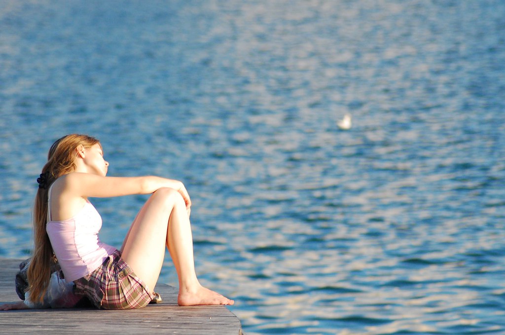 Image of teenager sitting near a lake