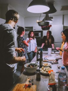 Deck the Halls (and the Kitchen)! A Real-Life Mallorcan Holiday Tale 18 A group of adults enjoying a casual dinner party in a cozy, modern kitchen setting.