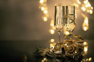 Champagne glasses with ribbons against festive bokeh lights.