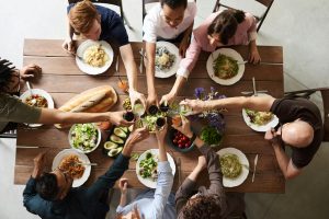 Deck the Halls (and the Kitchen)! A Real-Life Mallorcan Holiday Tale 14 A vibrant group cheers over a delicious meal, showcasing friendship and togetherness.