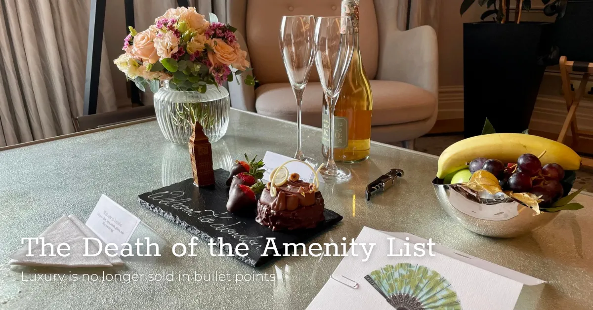 Elegant luxury hotel amenity tray featuring chocolate dessert, fresh fruit bowl, champagne, and welcome note on glass table.