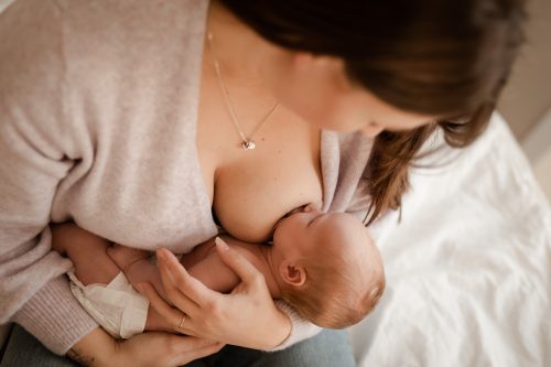 Nyfödd bebis ammar sin mamma under en nyföddfotografering i Stockholm