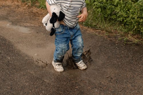 Ett barn som hoppar i en vattenpöl under en familjefotografering