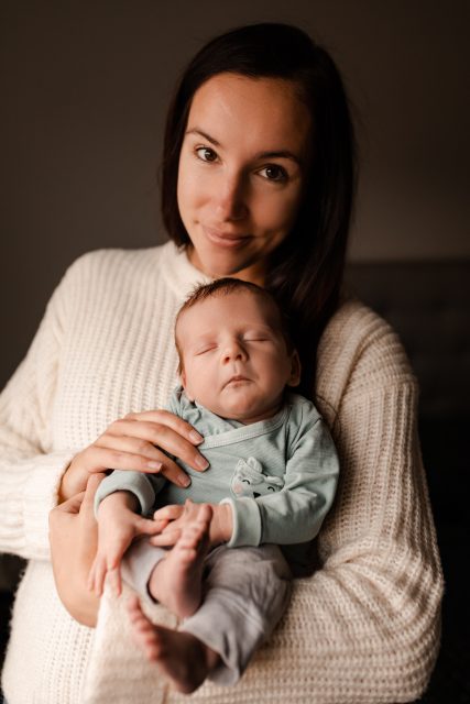 Brunhårig mamma håller sit nyfödda barn i famnen