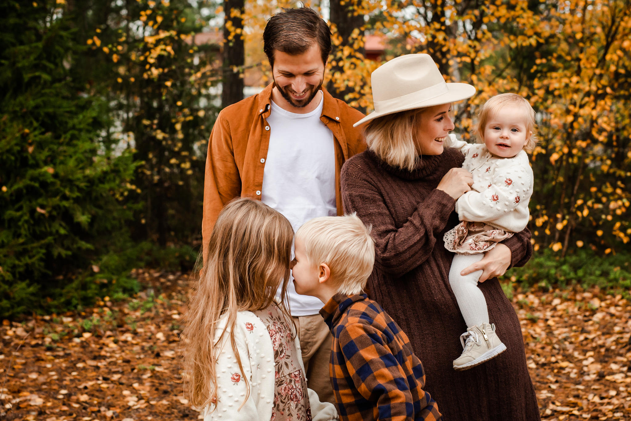 En familj som busar i höstfärgerna på sin familjefotografering i Stockholm