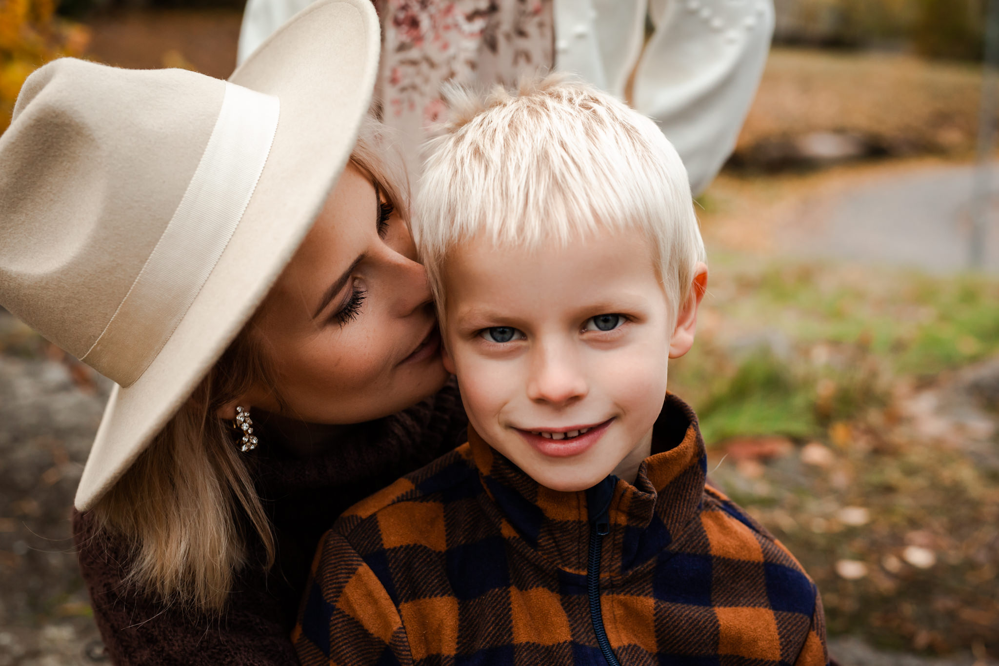 Familjefotografering utomhus i Stockholm där en mor pussar sin son på kinden