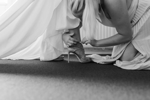 Brudtärna hjälper brud att sätta på skorna på bröllopsdagen