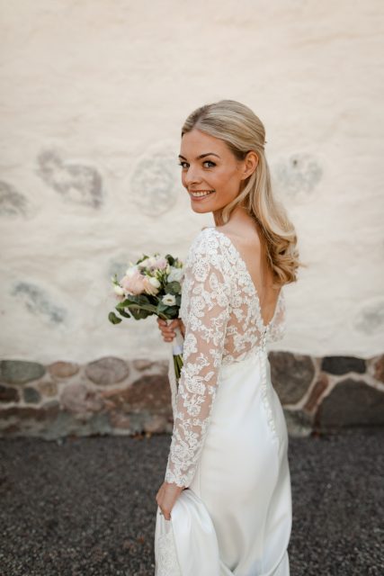 Blond kvinna står i brudklänning på sin bröllopsdag i Eksjö