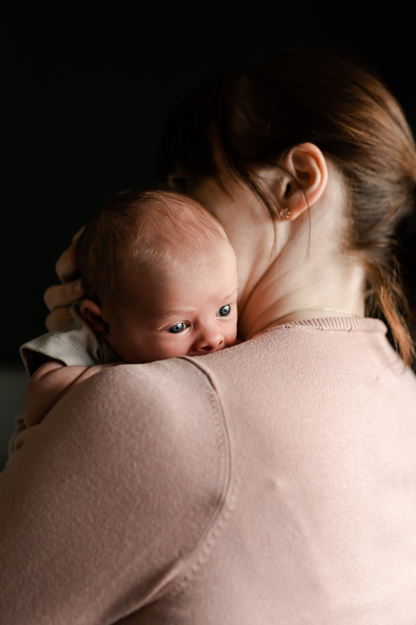 En mamma som håller sin nyfödda bebis mot axeln