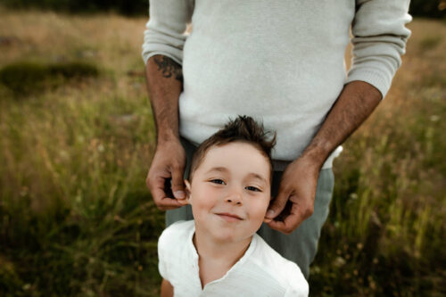 Ett barn står tillsammans med sin pappa på en familjefotografering utomhus i Eksjö