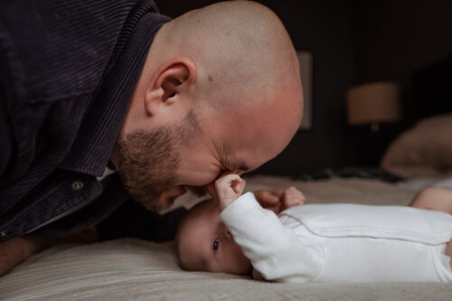 Nyfödd bebis boxar pappan i ögat under en nyföddfotografering i Småland