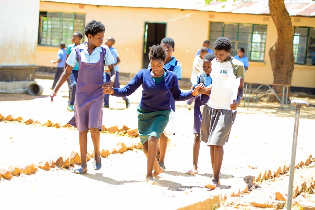 A girl named Misley in the schoolyard with her classmates.