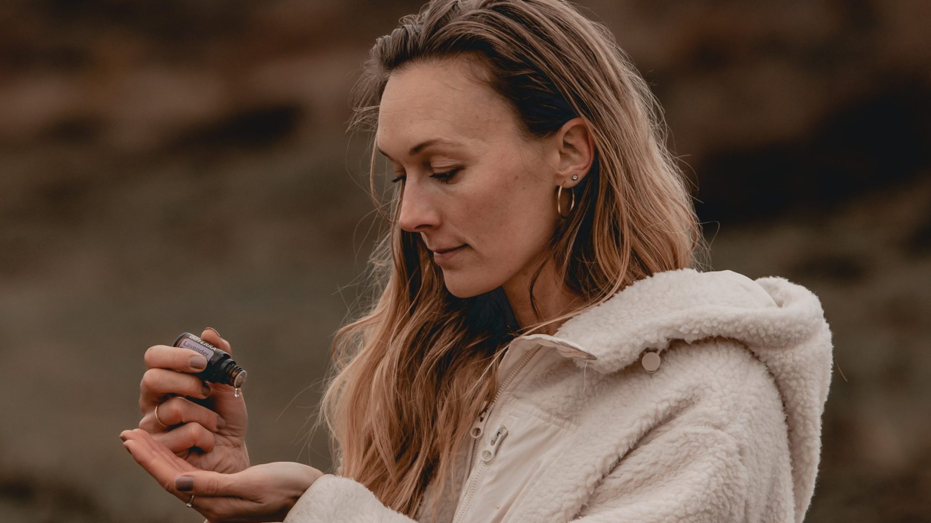 kvinde med jakke på hælder olie i sin hånd