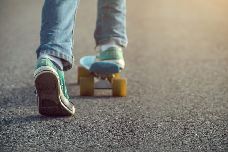 A young boy with jeans on a skateboard.