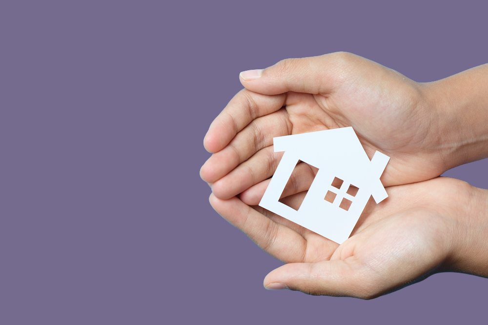 Two hands holding a paper cut out of a house.