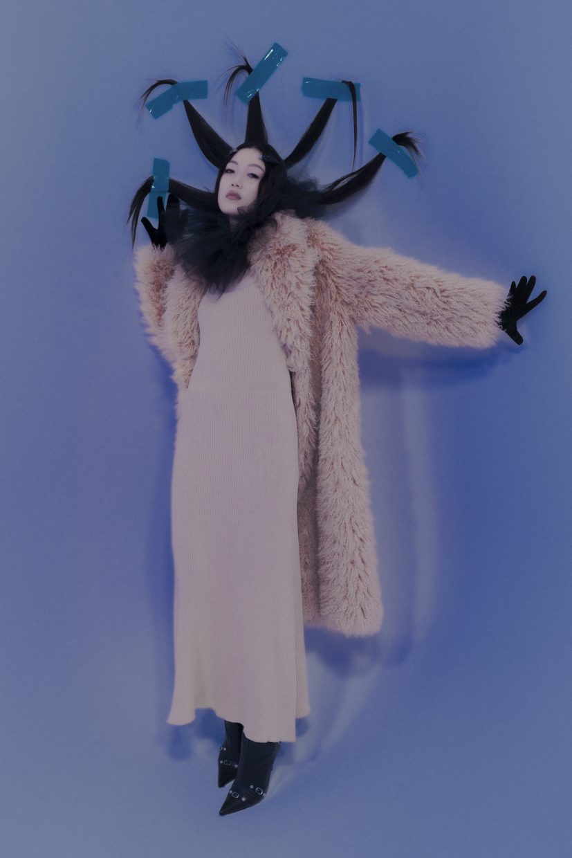 Model Loo Loo, fotografiert von Olga Urbanek, trägt ein langes weißes Kleid auf blauem Hintergrund