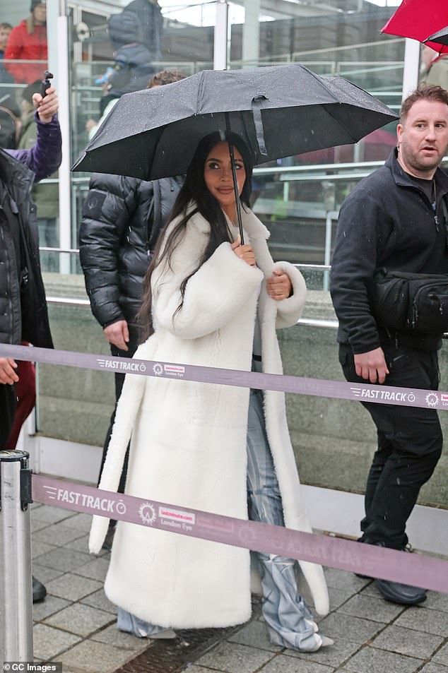 Rainy: Brandished with a large black umbrella, the reality star, 42, didn't let the dreary weather dampen her spirits as she arrived at the iconic landmark