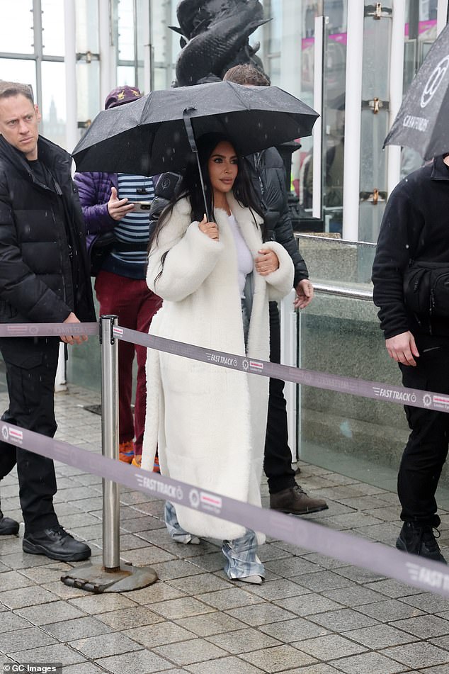 Off they go: Kim was wrapped up in a white fluffy coat and flanked by her hefty entourage as the group headed through the fast-track lane