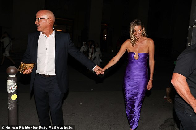 Grant was very much a gentleman carrying his girlfriend's gold clutch as they went to cross the road