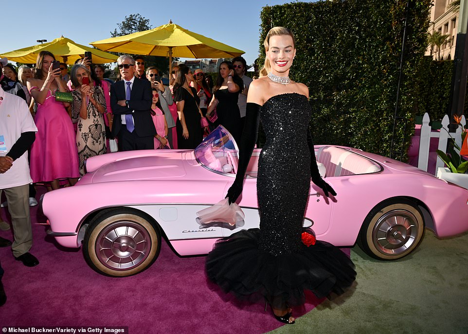 She's even clutching the pink chiffon scarf! Margot posed in front of a pink Chevrolet Corvette just like the one she drives in Barbie