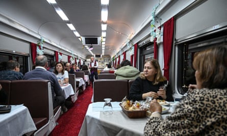 The dining carriage of the Doğu Express train filled with passengers at night.