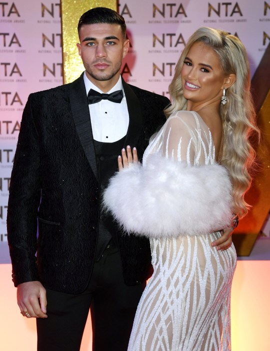 Tommy Fury and Molly-Mae Hague dressed up in black tie at an event. They are smiling and hugging