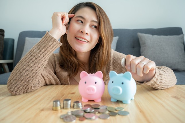 Woman planning about her financial while putting a coin into piggy bank for saving money.