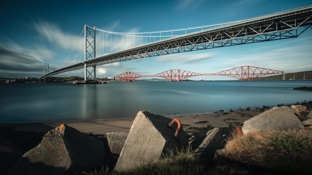 A bridge over water with wispy clouds in a blue sky in the background