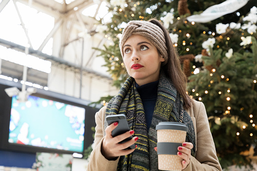 Woman waiting at station looking up at departure board.