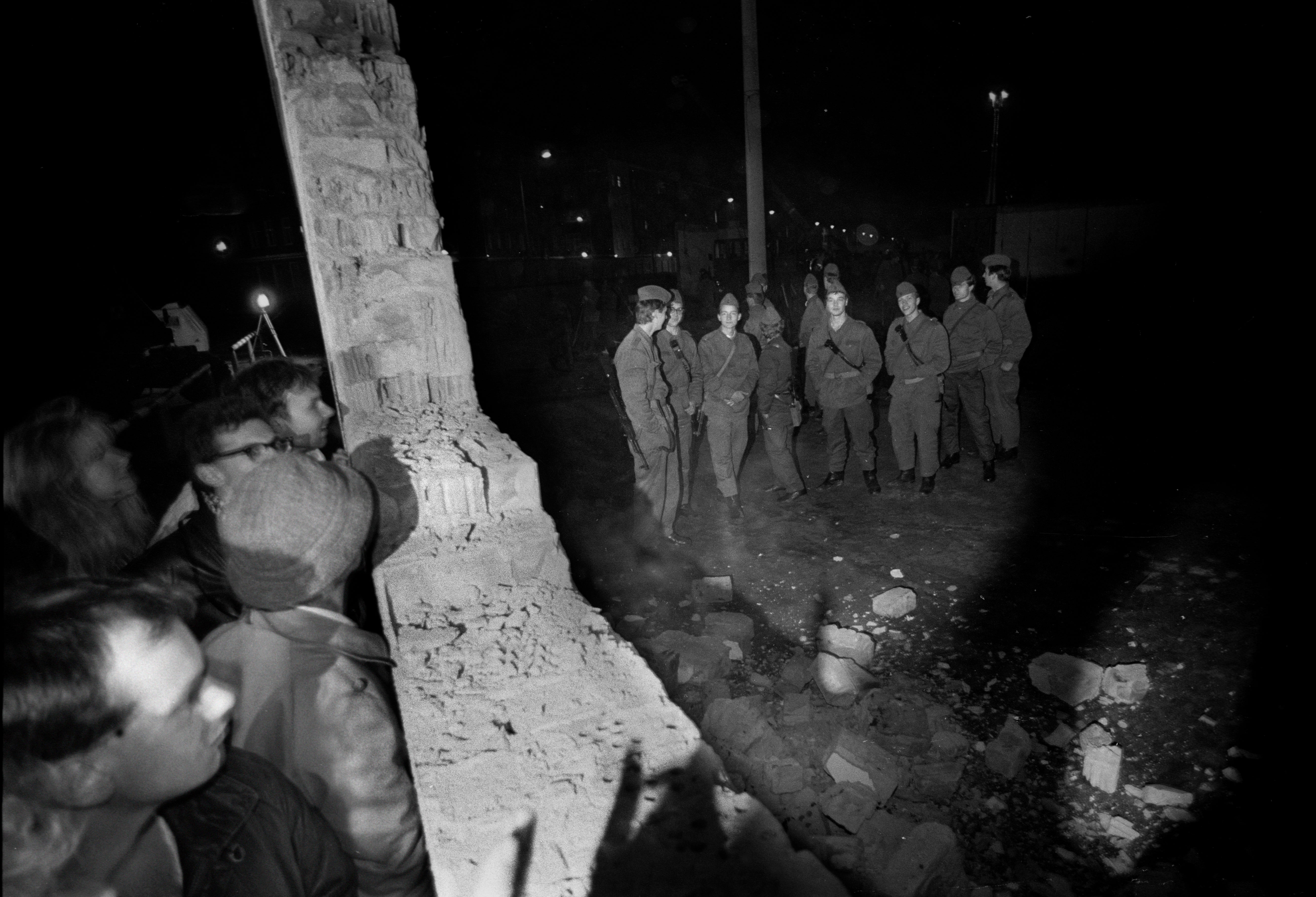 The first breach in the Berlin Wall at 10.30pm on 9 November 1989. East German border guards look on from the ‘Death Strip’