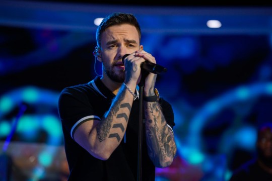 Liam Payne singing into a microphone, wearing a black t-shirt