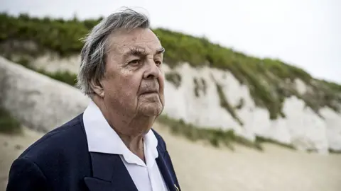 BBC/Hardcash Productions/Simon Rawles John Folkes looks out to sea, white cliffs behind him.