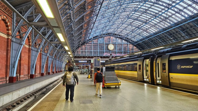 London, England, United Kingdom -September 19th 2024 : Rear view of two passengers walking on the railway station platform of St Pancras International Station , Unit 37D in London. London St Pancras International Station is the terminus for Eurostar services from Belgium, France and the Netherlands to London.