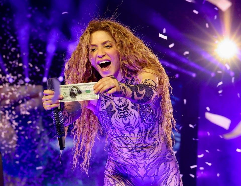 Shakira holding a modified $100 bill onstage.