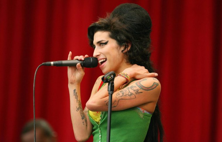 Pilton, UNITED KINGDOM: British pop singer Amy Winehouse performs at the Glastonbury music festival, in Pilton, Somerset, in south-west England, 22 June 2007. The Glastonbury Festival kicked off Friday with Arctic Monkeys and Bjork headlining as rain began to turn the vast site into the traditional mudbath. The planet's largest greenfield music and performing arts festival is back and bigger than ever after taking a break in 2006, with 177,500 people packing out Worthy Farm in southwest England, to catch some of the world's hottest acts. But the 800 acres (320 hectares) of rolling Somerset countryside was gradually descending into a muddy bog as heavy rain soaked the giant tent city. AFP PHOTO/CARL DE SOUZA (Photo credit should read CARL DE SOUZA/AFP via Getty Images)