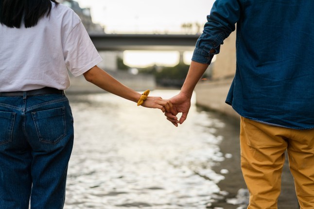 Couple holding hands looking out at the River Seine in France