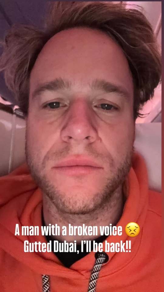 Close-up selfie of a man with a broken voice, wearing an orange hoodie.  Text overlay reads: "A man with a broken voice 😭 Gutted Dubai, I'll be back!!"