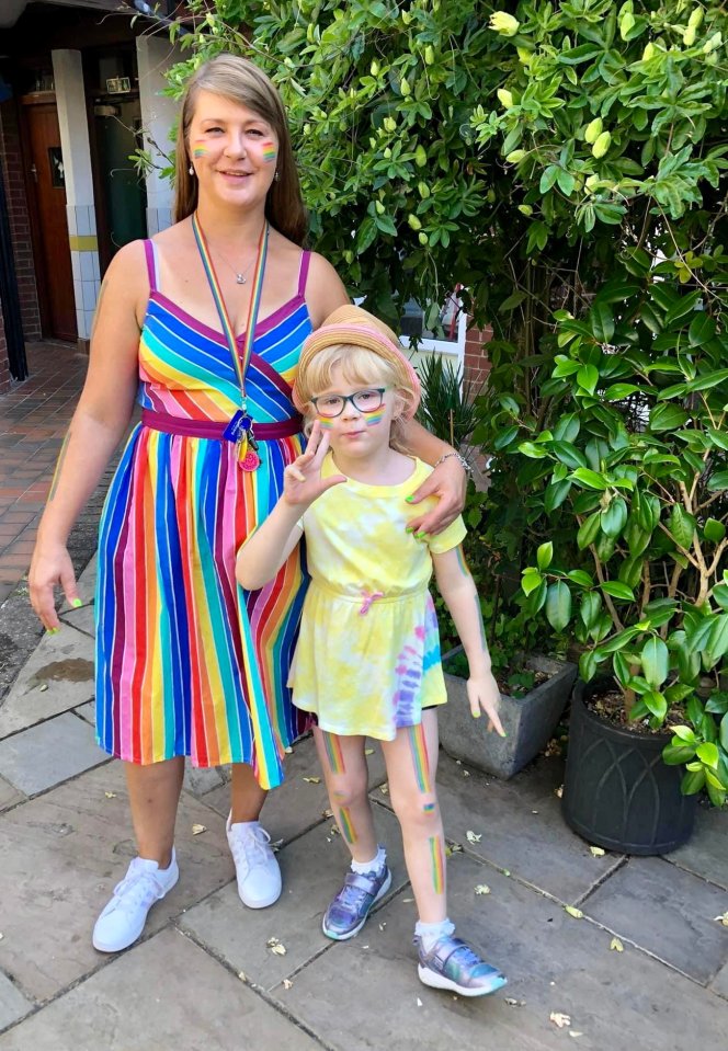 A mother and daughter with rainbow-themed face paint and clothing.