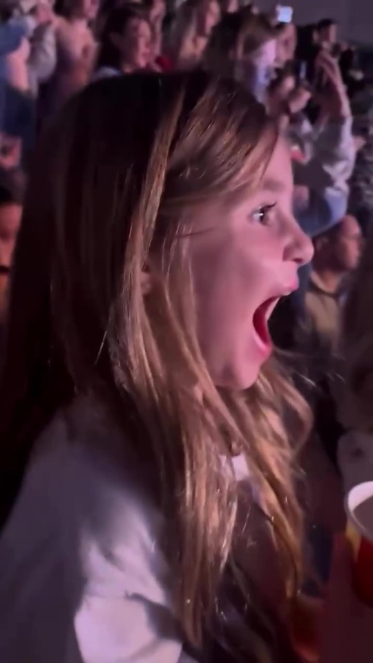 Girl with surprised expression at concert.