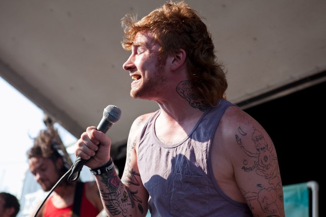 Jonny Craig performing onstage in 2010. He is singing into a microphone while wearing a grey vest