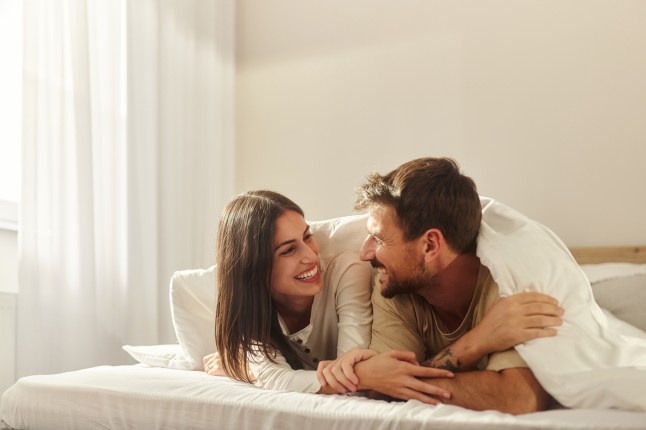 Happy couple talking during morning in a bed.