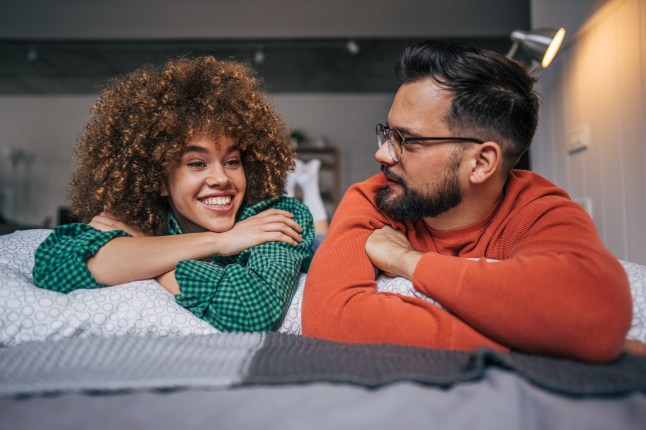 Couple have a light-hearted conversation while lying on the bed.